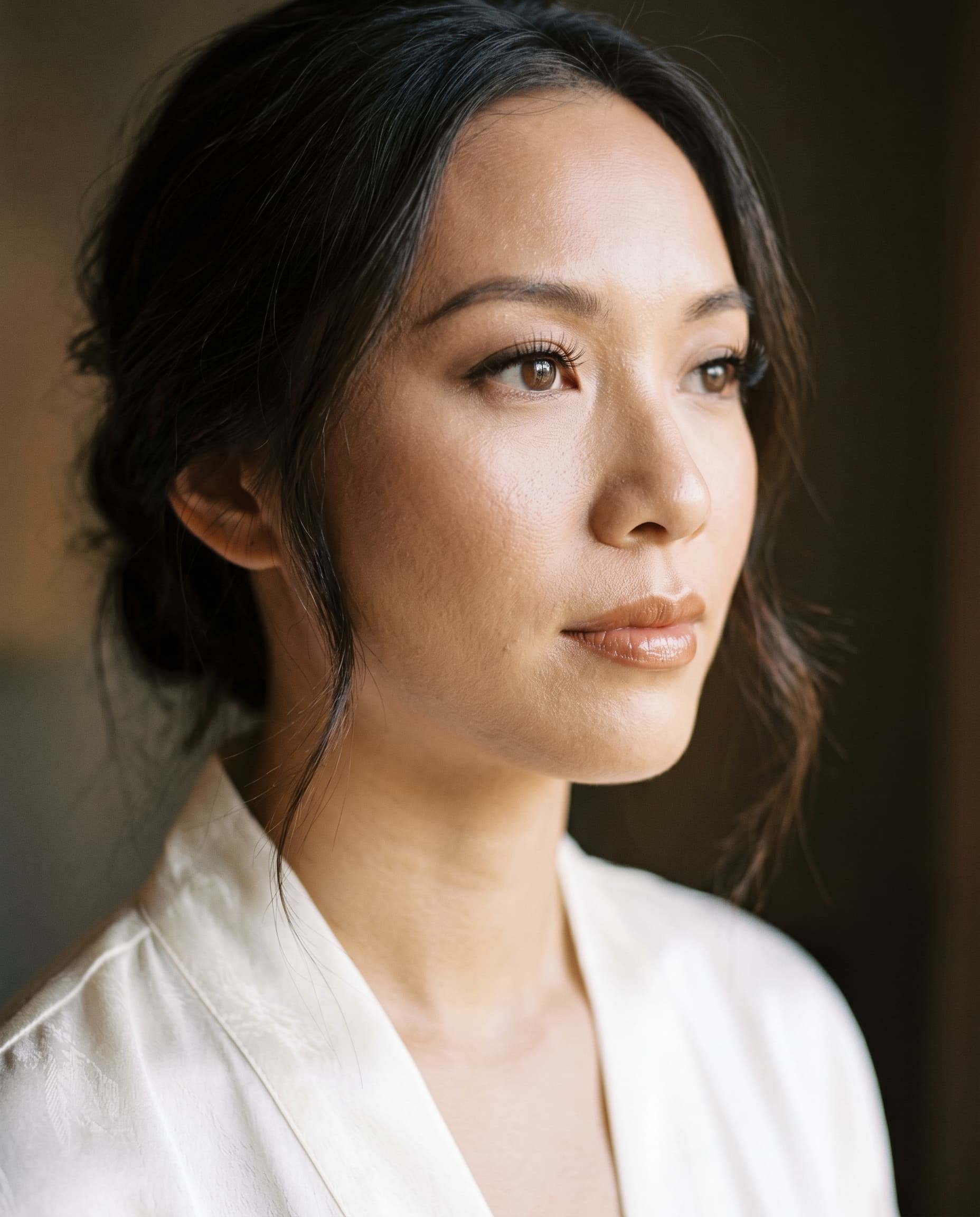 Bride in an ivory silk robe, soft glam makeup, calm and ready.